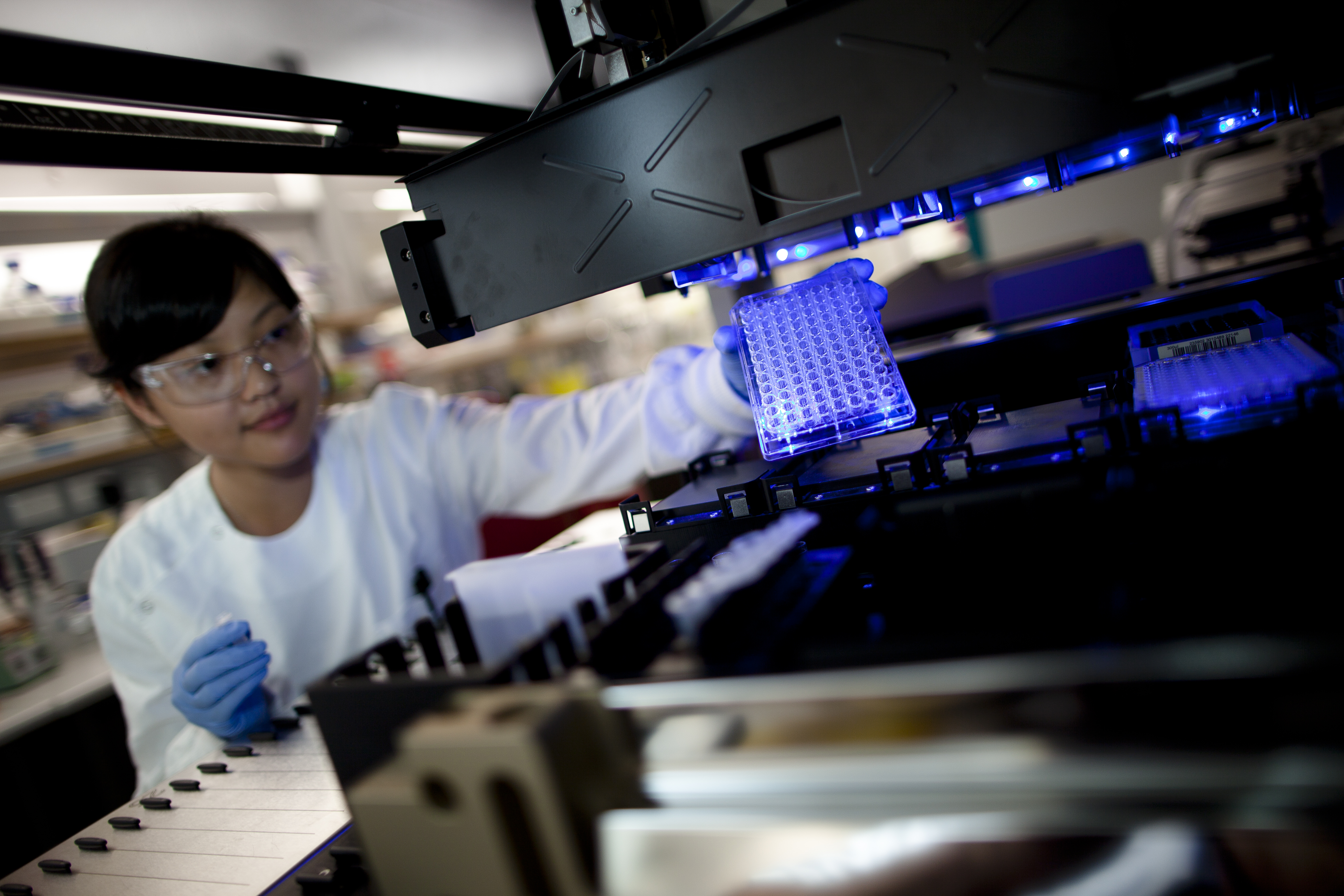 Researcher loading a microplate into automation