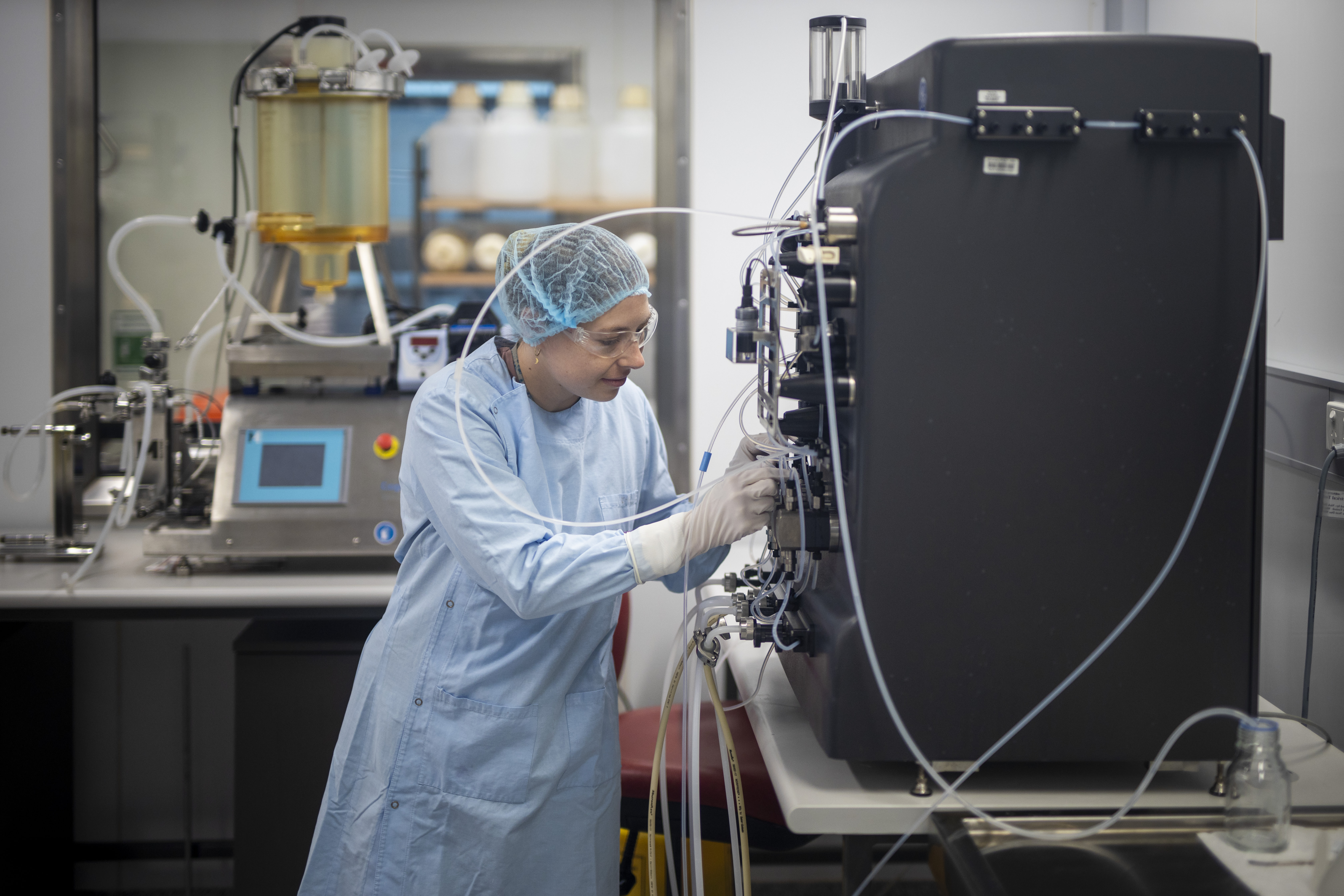 Researcher in a cleanroom operating a bioprocessing rig