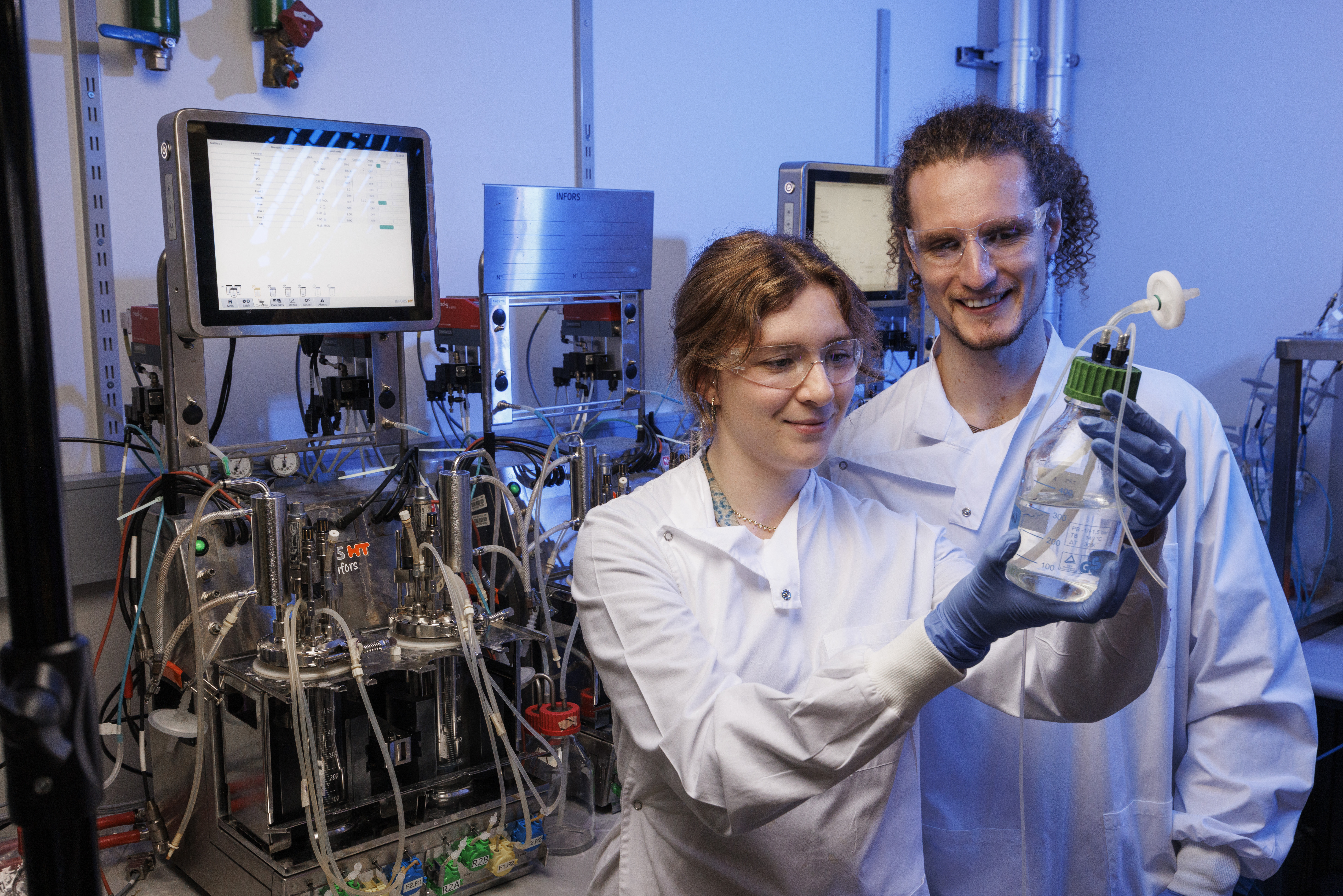 Two scientists inspecting a media bottle at the bioreactors